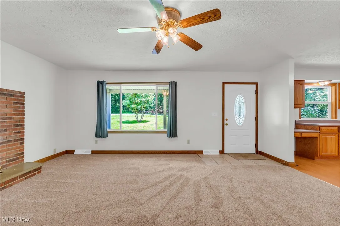 Foyer entrance with a textured ceiling, light carpet, and ceiling fan