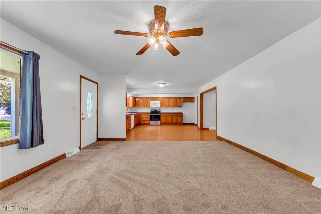 Unfurnished living room with light colored carpet and a ceiling fan