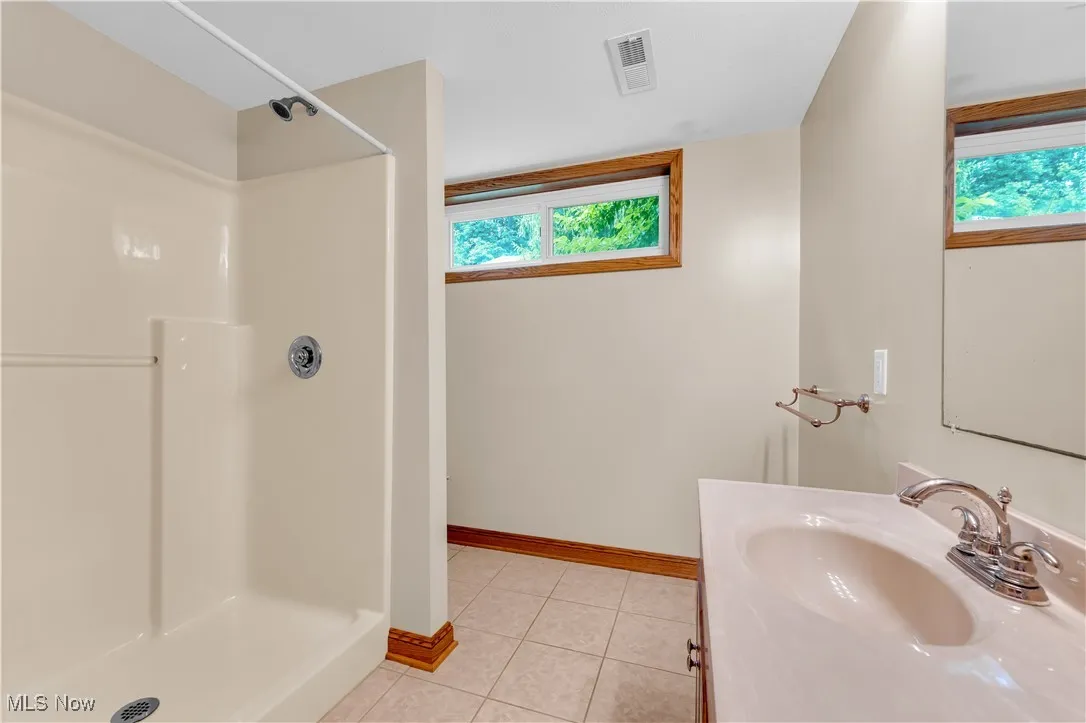 Full bathroom featuring a shower, tile patterned floors, and vanity