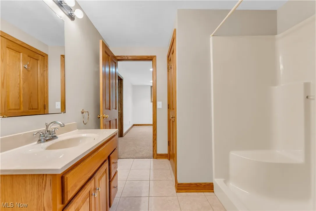 Bathroom with vanity, a shower, and tile patterned flooring