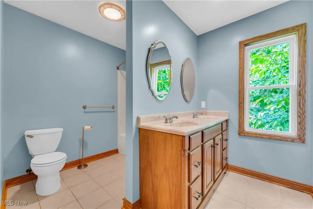 Bathroom with plenty of natural light, double vanity,  shower combination, and tile patterned floors