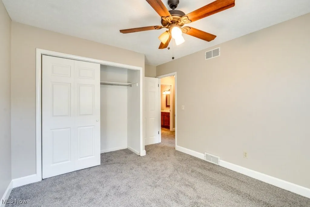 Unfurnished bedroom with carpet, a closet, and a ceiling fan