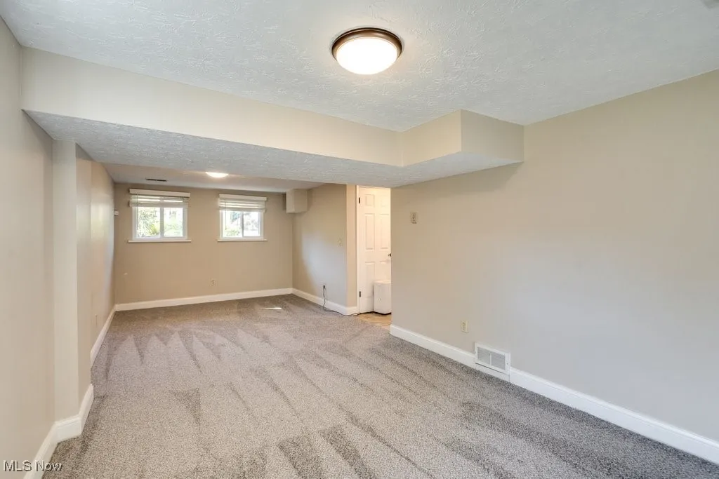 Basement featuring a textured ceiling and carpet flooring