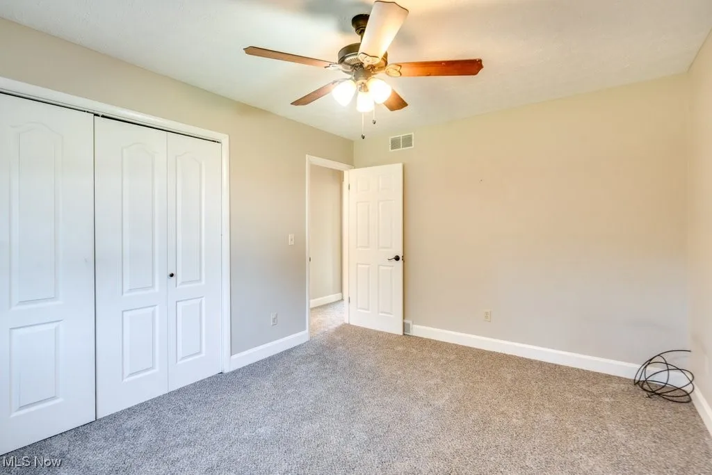 Unfurnished bedroom featuring carpet floors, a closet, and ceiling fan