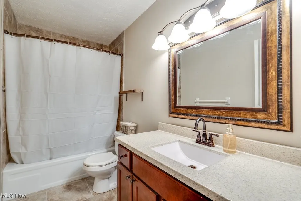 Full bathroom with vanity, a textured ceiling, and shower / bathtub combination with curtain
