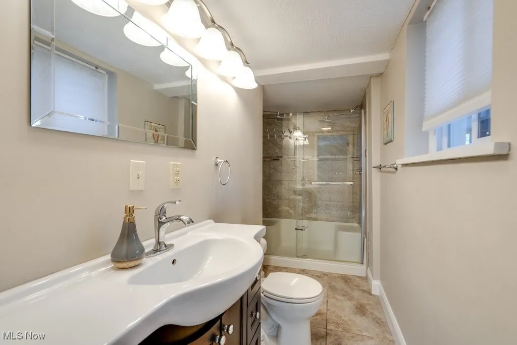 Full bath with a shower stall, vanity, and tile patterned floors