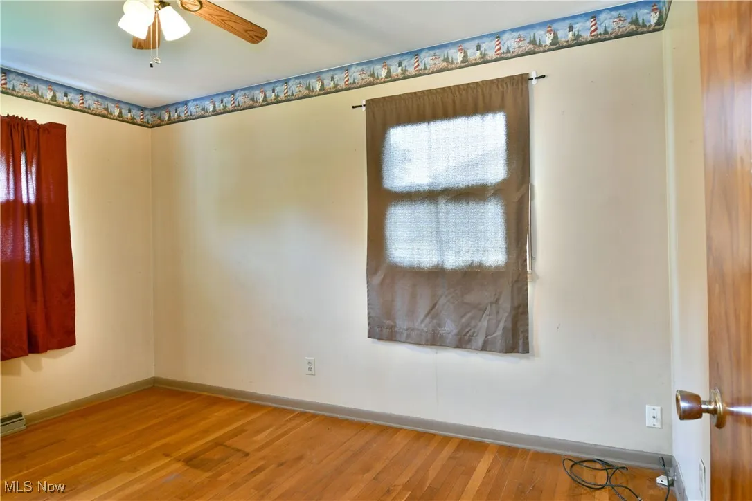 Empty room with wood finished floors and ceiling fan