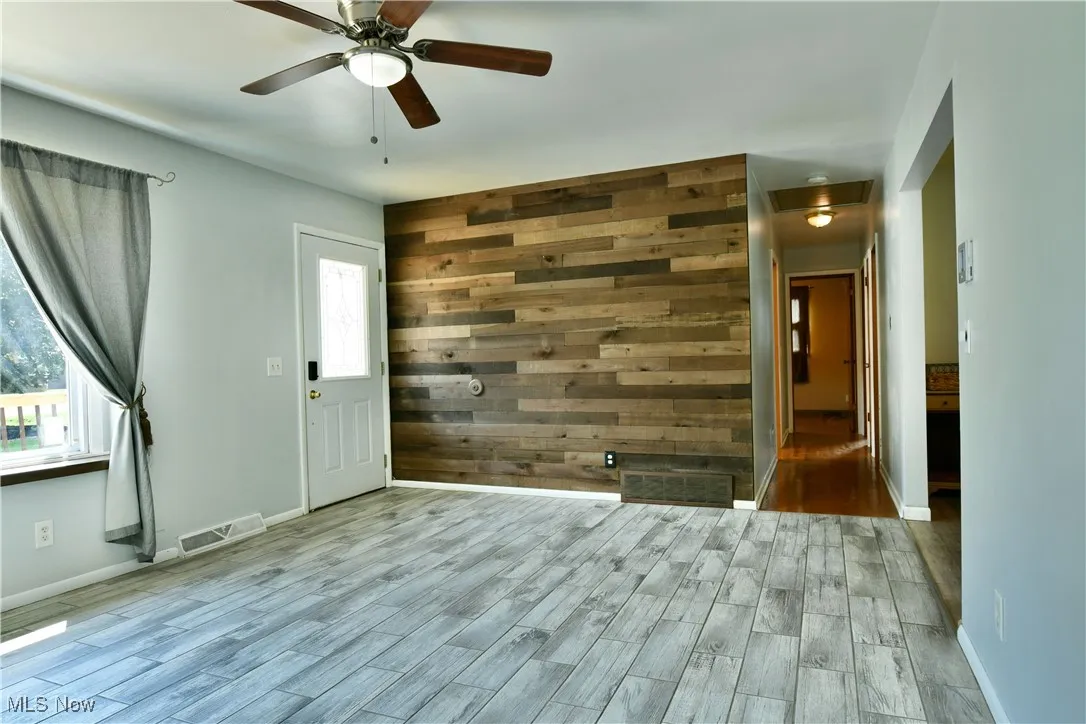 Spare room featuring wood finished floors, ceiling fan, and wood walls