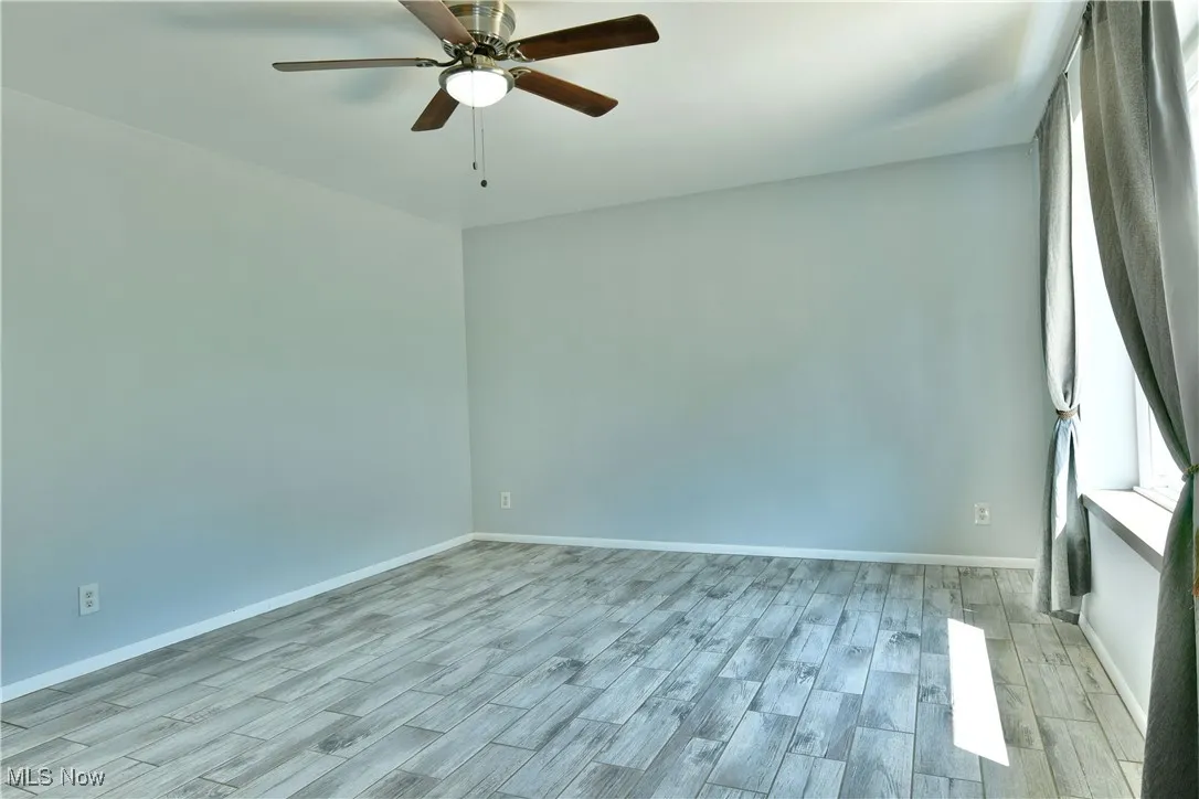 Empty room with a ceiling fan and light wood-style floors