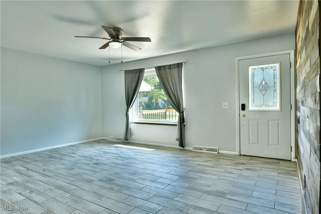 Foyer entrance with ceiling fan and light wood-style flooring