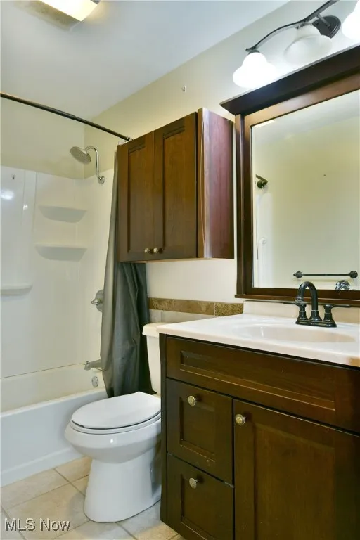 Full bath with vanity, tile patterned flooring, and shower / bath combo with shower curtain