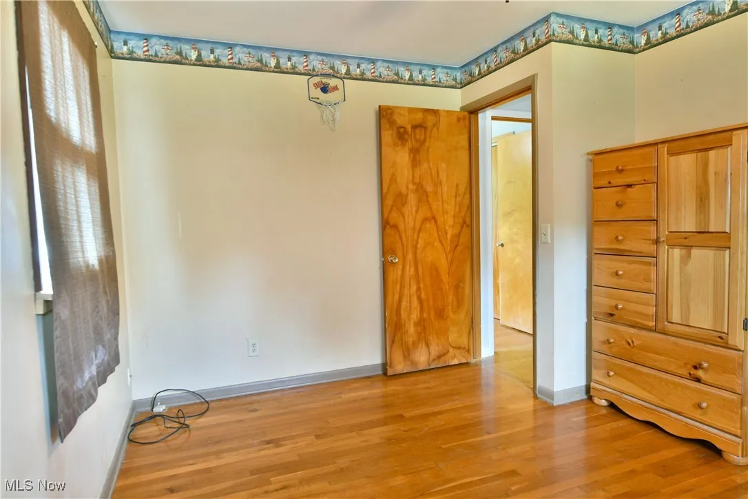 Unfurnished bedroom featuring wood finished floors and baseboards