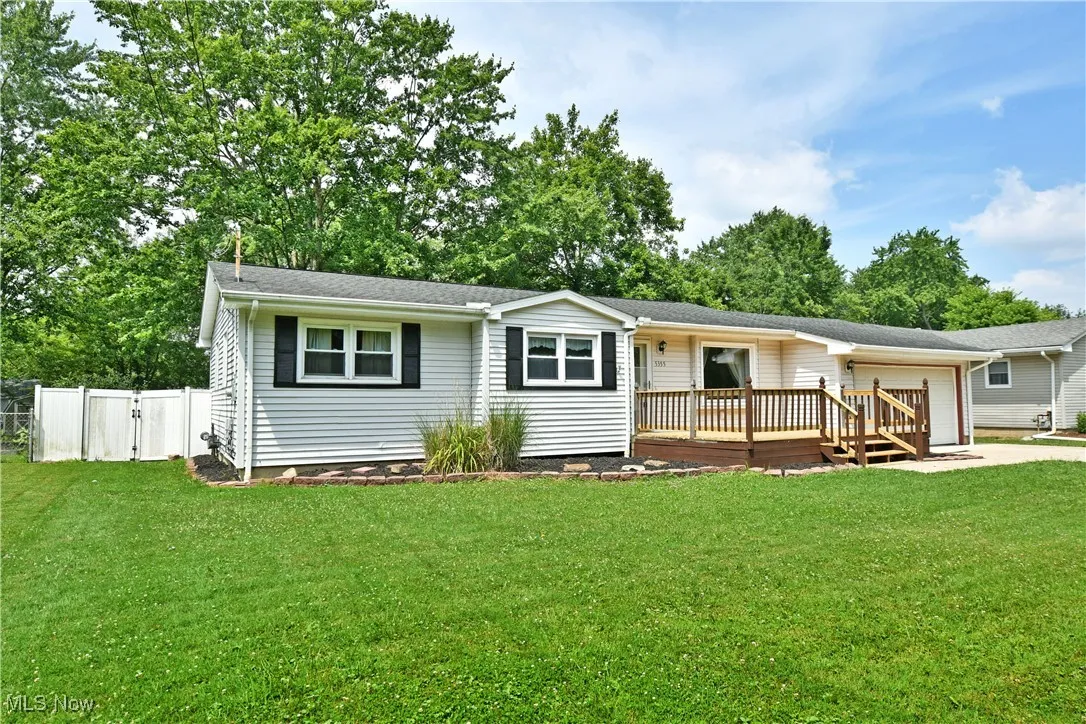 View of front of home featuring a garage, a deck, concrete driveway, and roof with shingles