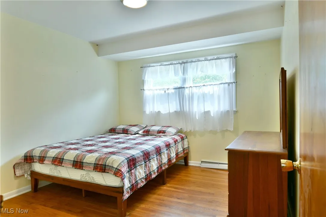Bedroom featuring wood finished floors and a baseboard radiator