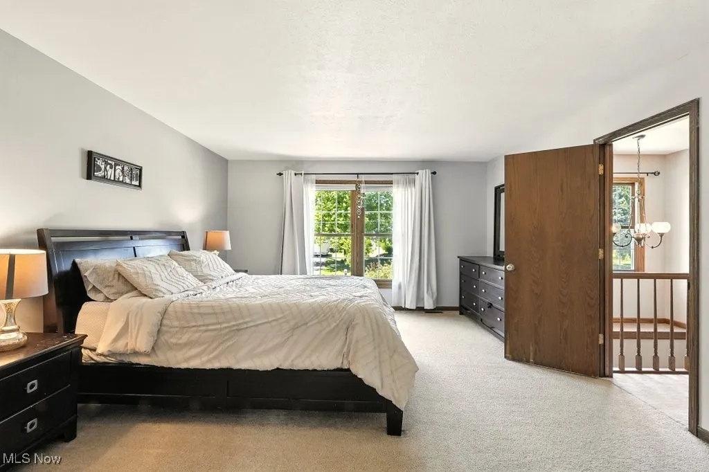 Bedroom with a chandelier, light carpet, and a textured ceiling