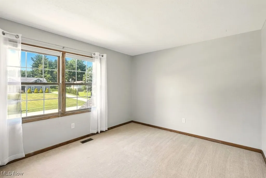 Unfurnished room with light colored carpet and baseboards