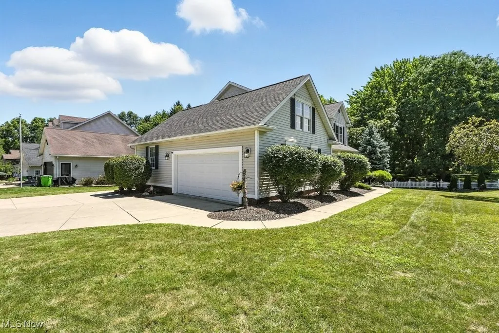 View of home's exterior featuring concrete driveway, a garage, a lawn, and a shingled roof