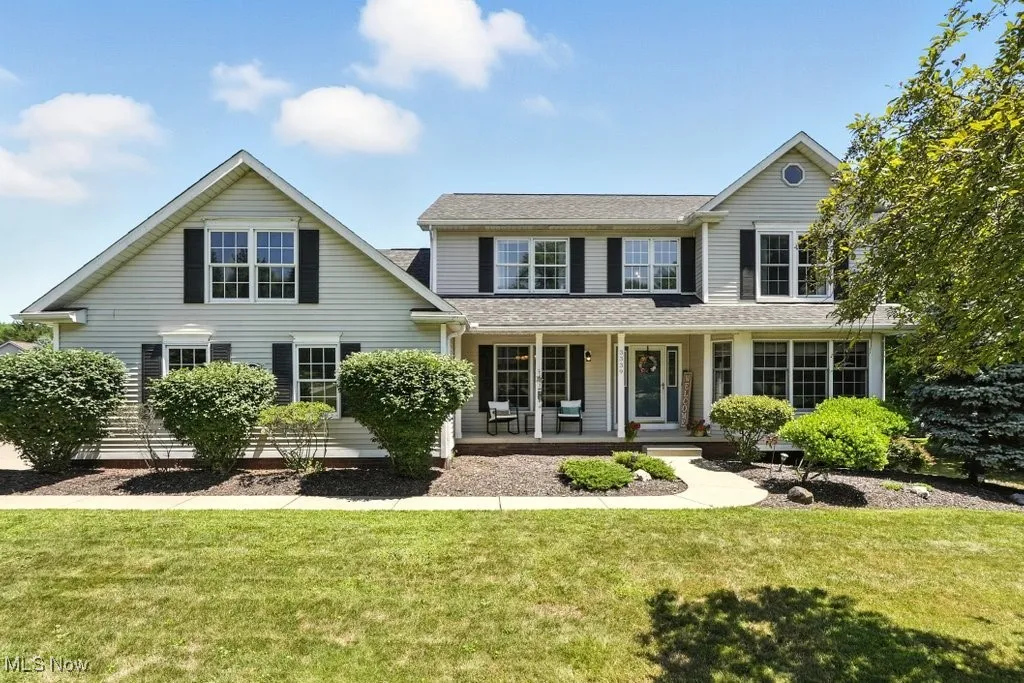 Back of property featuring covered porch, a lawn, and roof with shingles