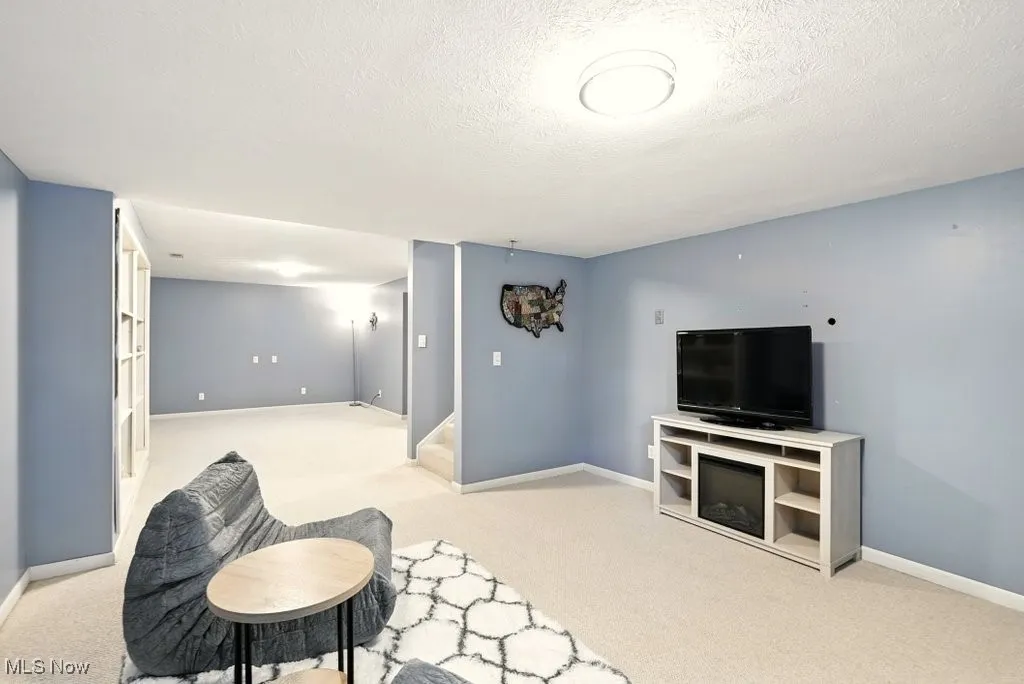 Living area with light colored carpet, stairway, and a textured ceiling