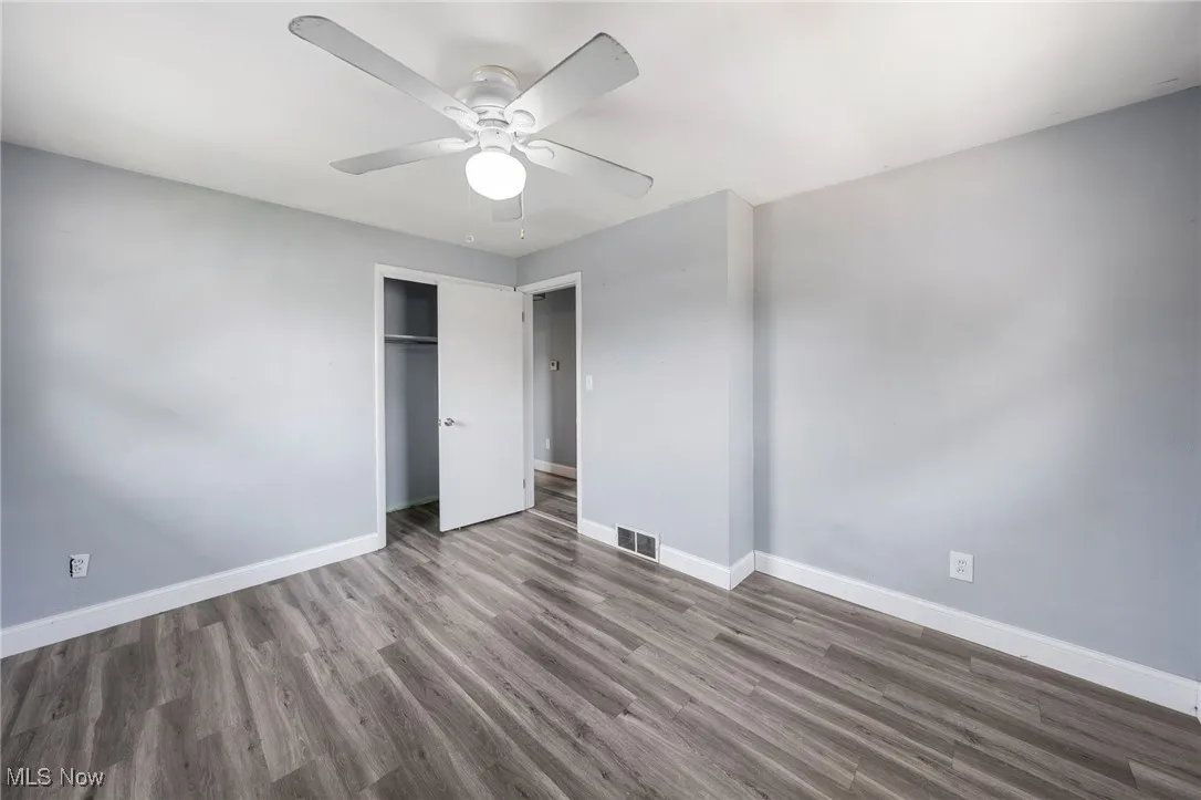 Unfurnished bedroom featuring wood finished floors, a closet, and a ceiling fan