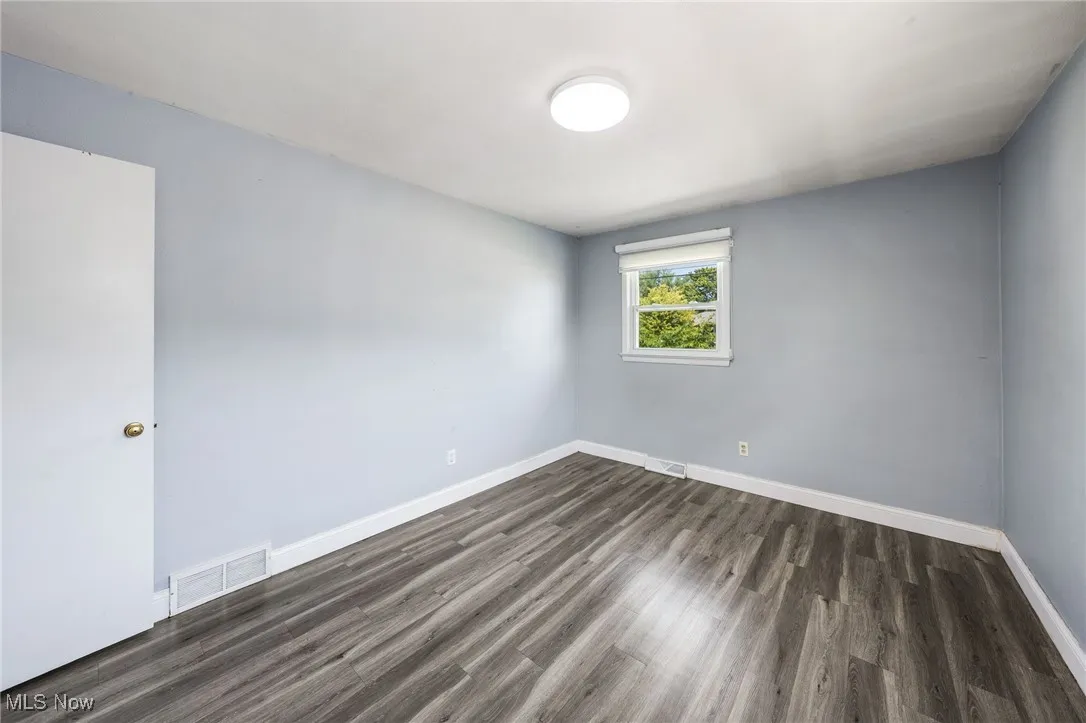 Spare room with dark wood-style floors and baseboards
