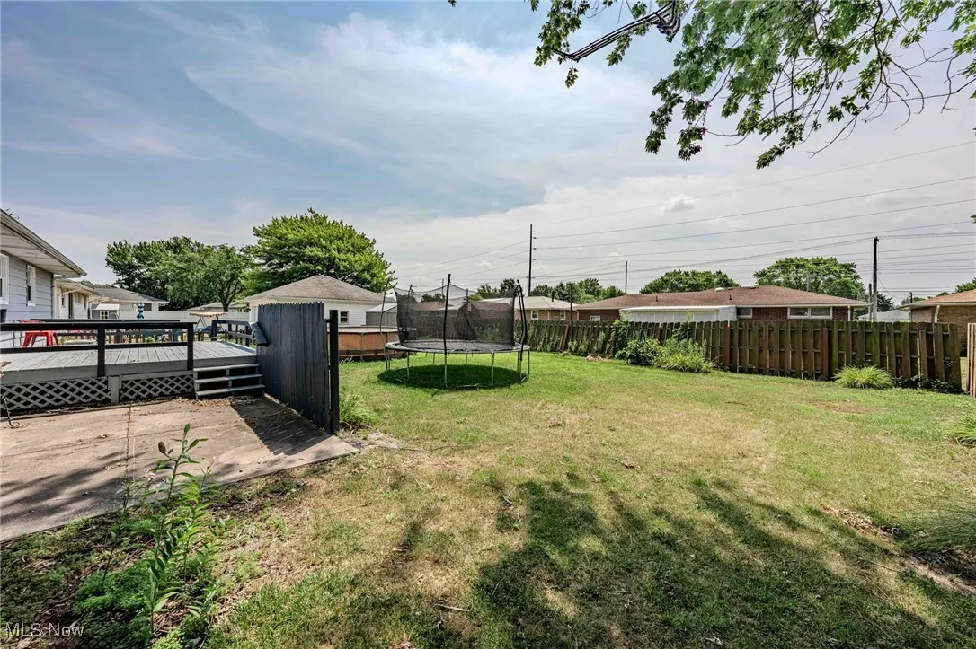 Fenced backyard with a trampoline and a wooden deck