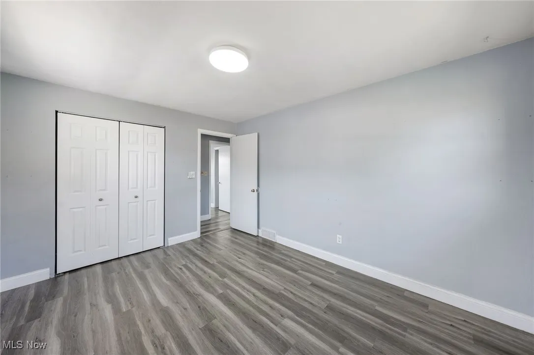 Unfurnished bedroom with wood finished floors and a closet