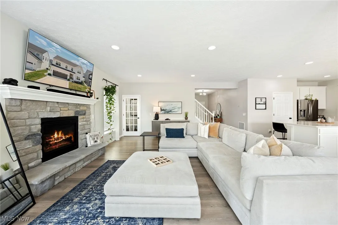 Living area featuring a fireplace, recessed lighting, wood finished floors, and stairs