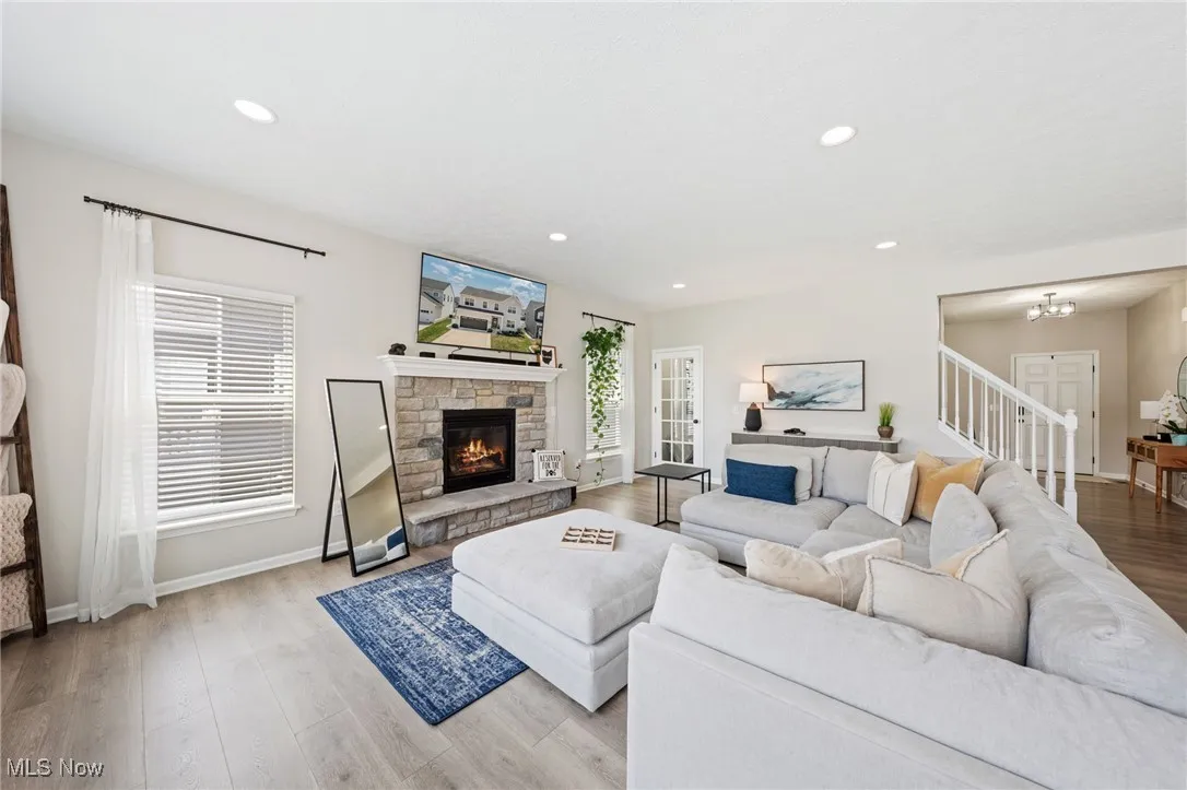 Living room with light wood-style flooring, a fireplace, recessed lighting, and a chandelier