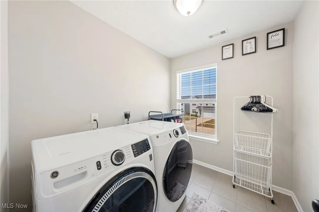 Laundry area featuring washing machine and clothes dryer and light tile patterned flooring