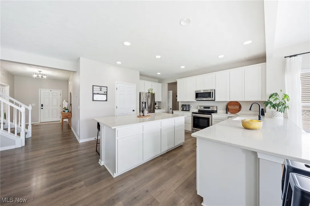 Kitchen with a kitchen breakfast bar, dark wood-style flooring, light countertops, recessed lighting, and white cabinetry