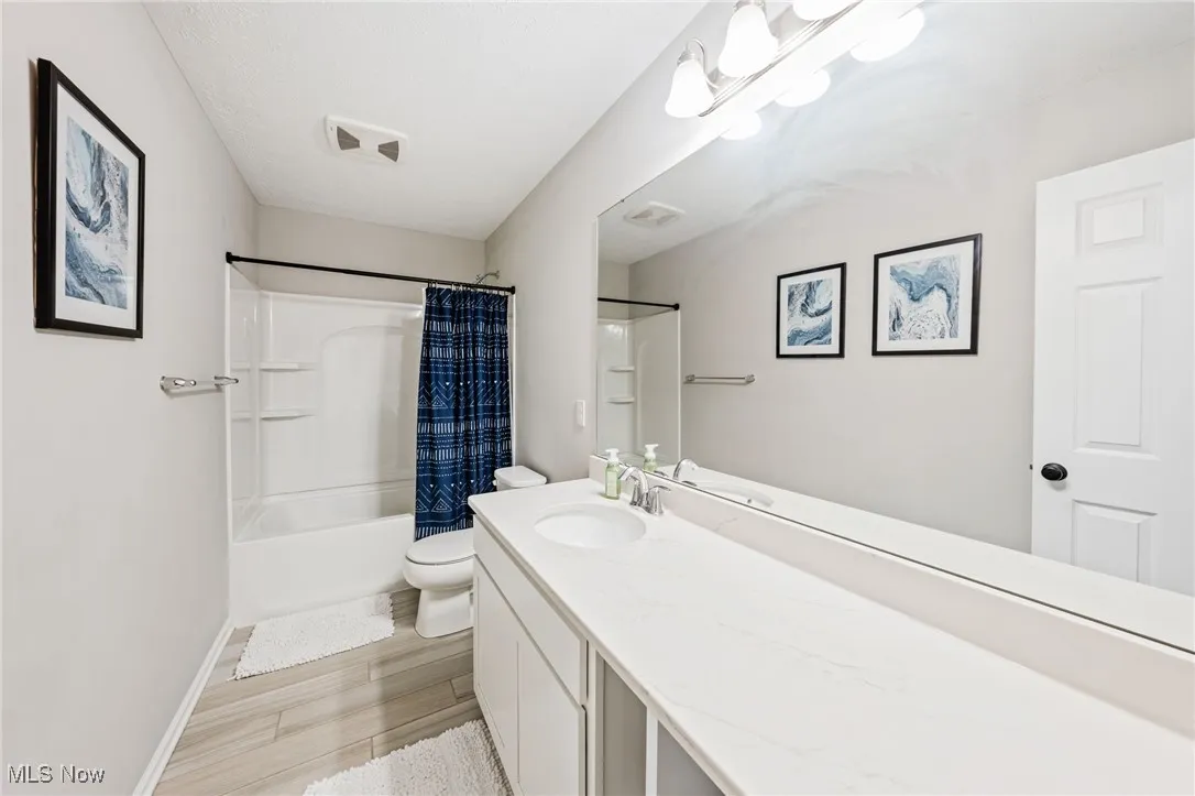 Bathroom with vanity, shower / bath combo, and wood finished floors