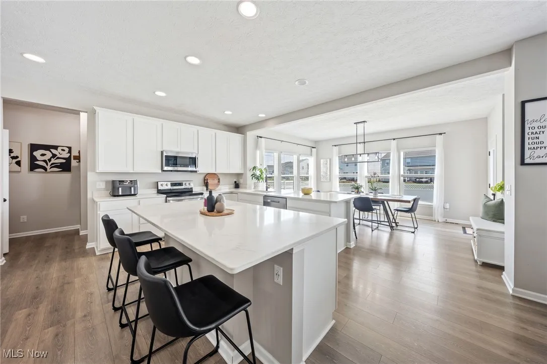 Kitchen featuring a peninsula, a kitchen island, a breakfast bar area, recessed lighting, and appliances with stainless steel finishes