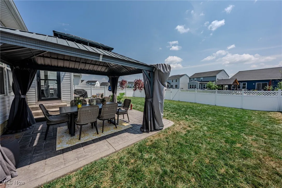 Fenced backyard with a gazebo, a patio area, a residential view, and outdoor dining space