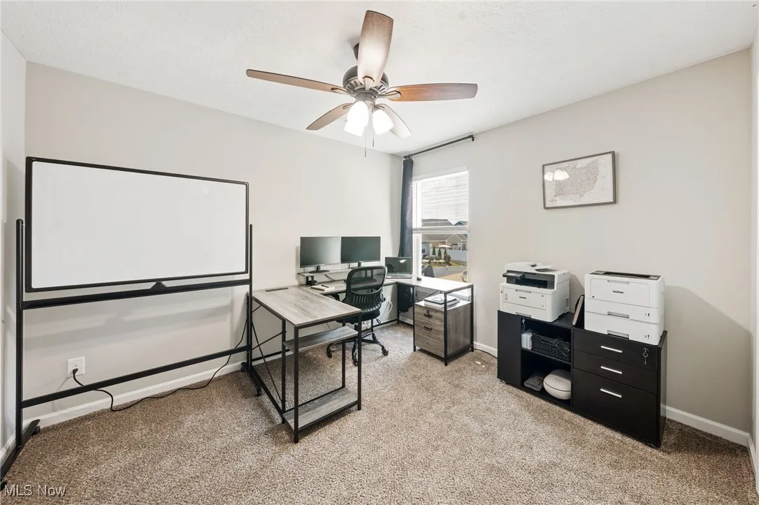 Home office featuring light colored carpet and a ceiling fan