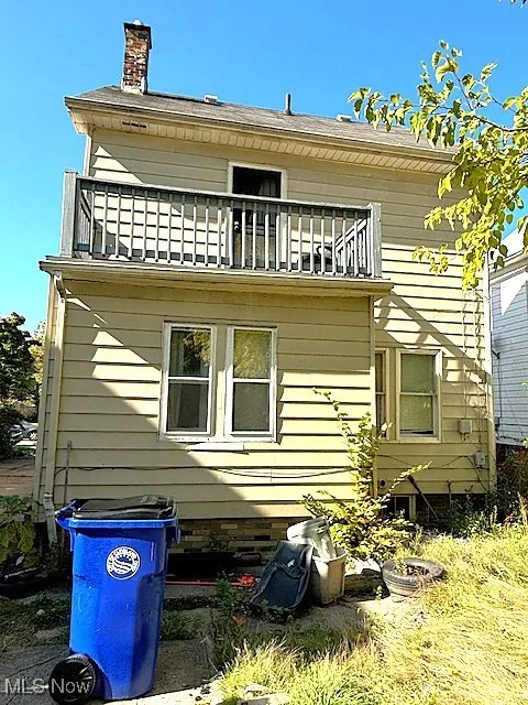 Rear view of house featuring a balcony and a chimney