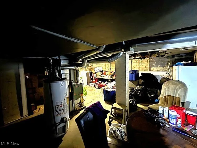 Unfinished basement with gas water heater and fridge