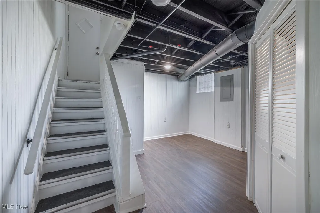 Stairs featuring wood finished floors and electric panel