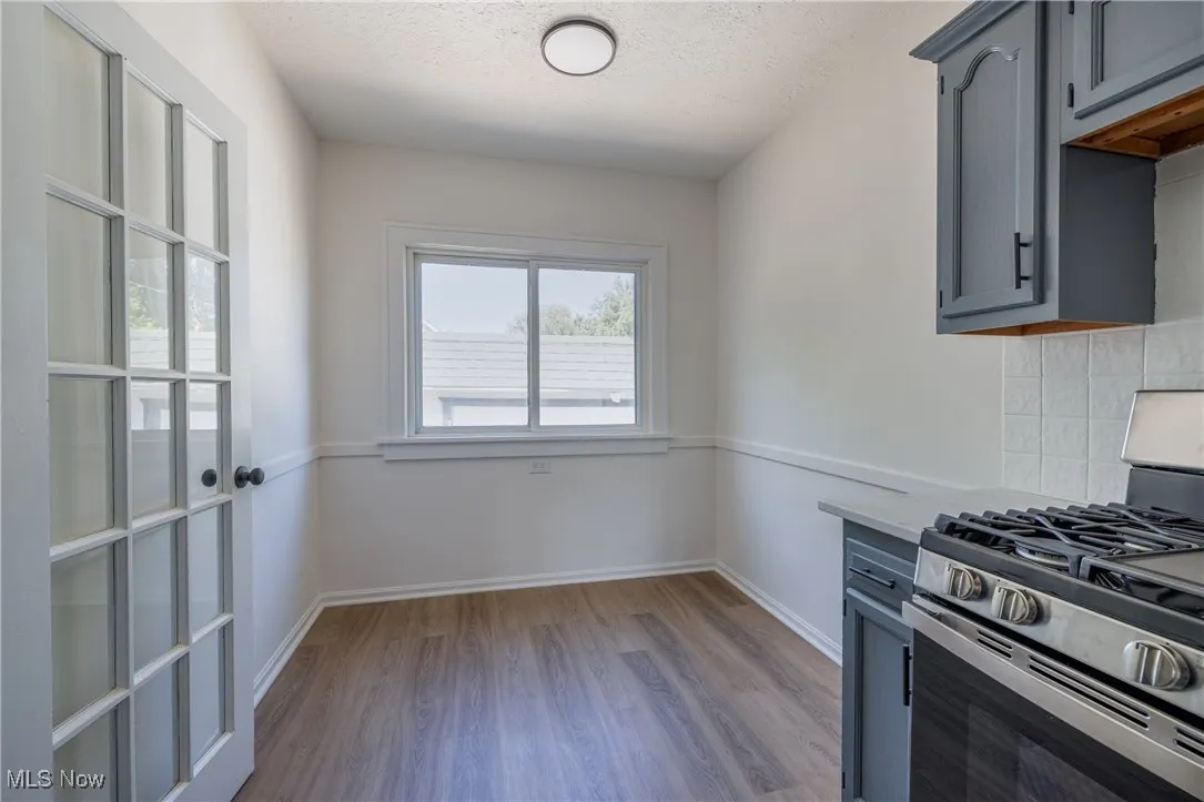 Kitchen featuring stainless steel gas stove, gray cabinets, wood finished floors, light countertops, and a textured ceiling