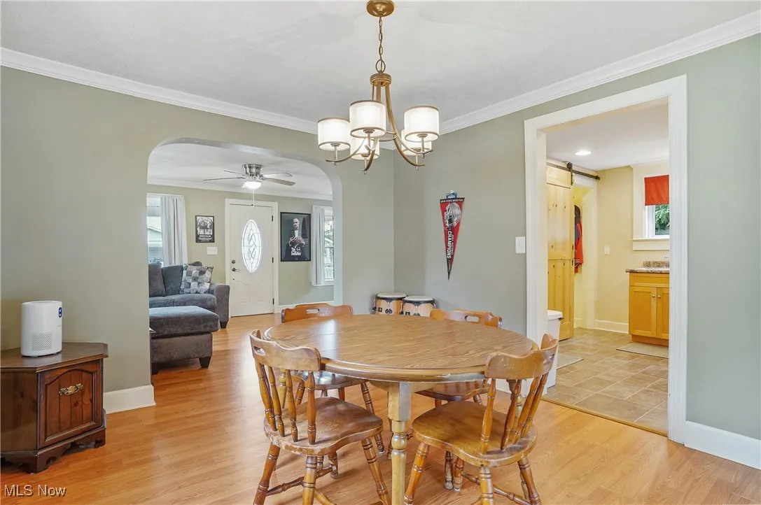 Dining area featuring arched walkways, ornamental molding, a chandelier, light wood finished floors, and ceiling fan