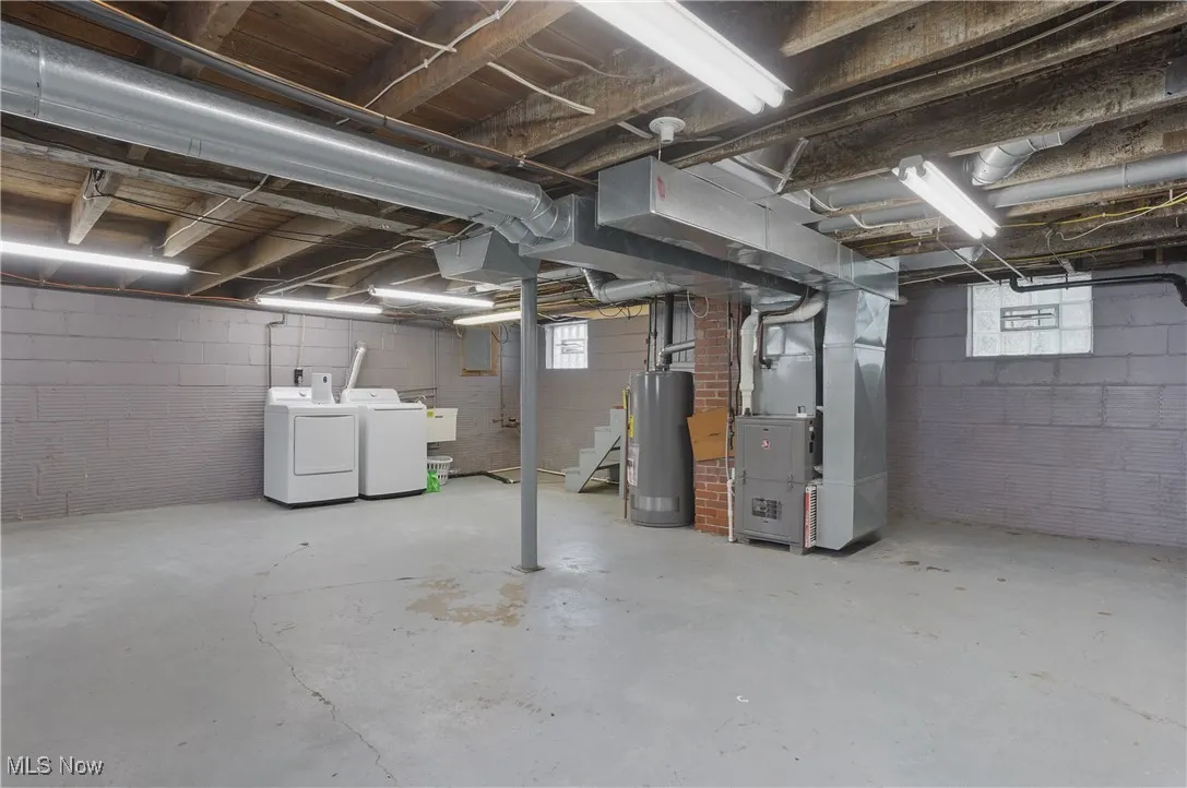 Below grade area with washing machine and dryer, stairs, heating unit, water heater, and plenty of natural light