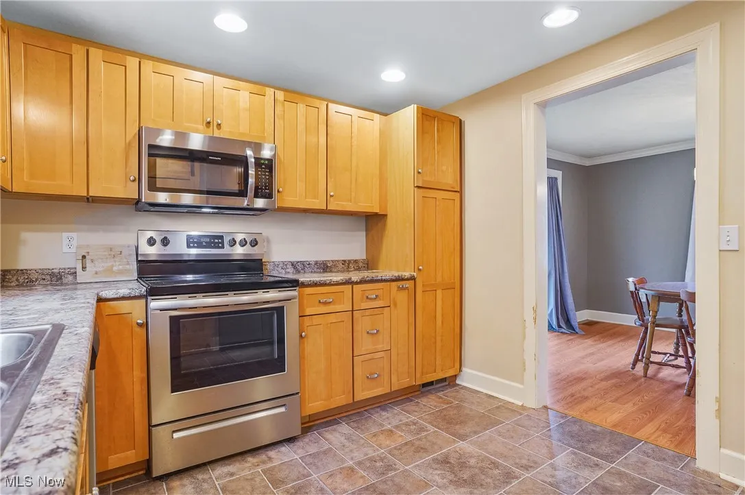 Kitchen featuring appliances with stainless steel finishes, recessed lighting, and ornamental molding