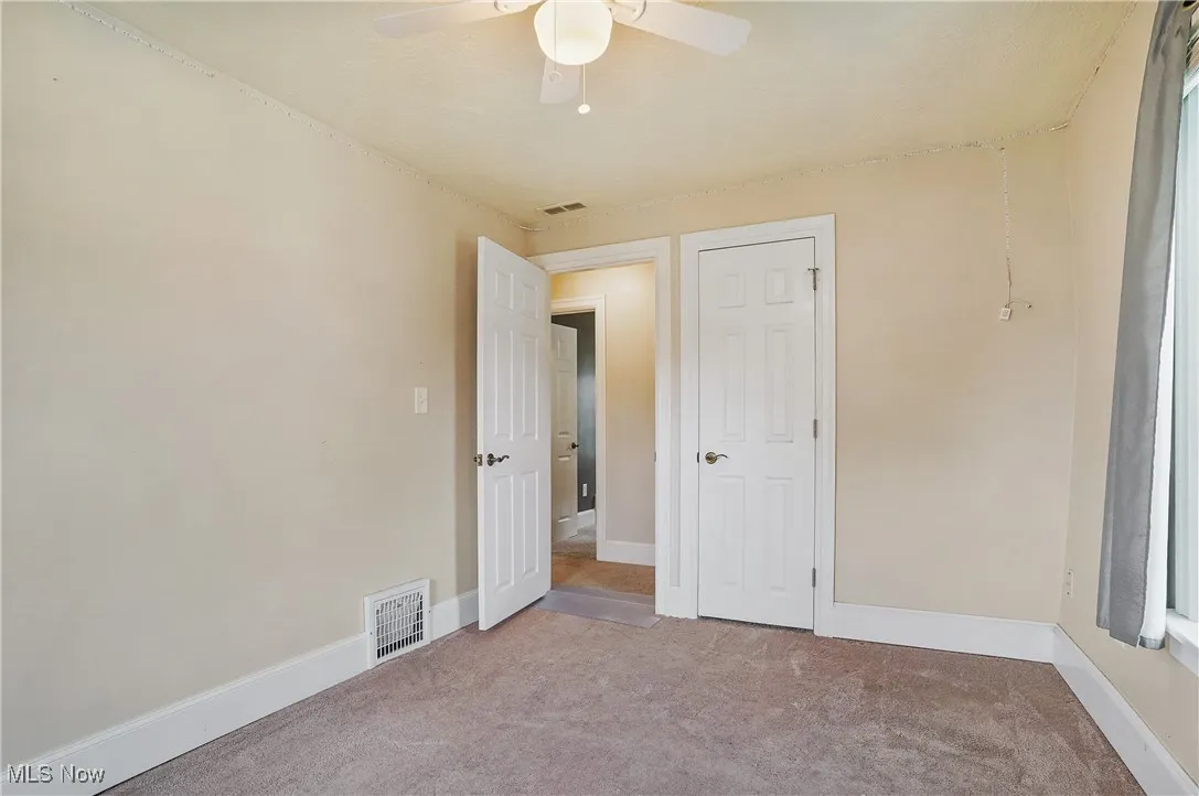 Carpeted spare room with ceiling fan and baseboards