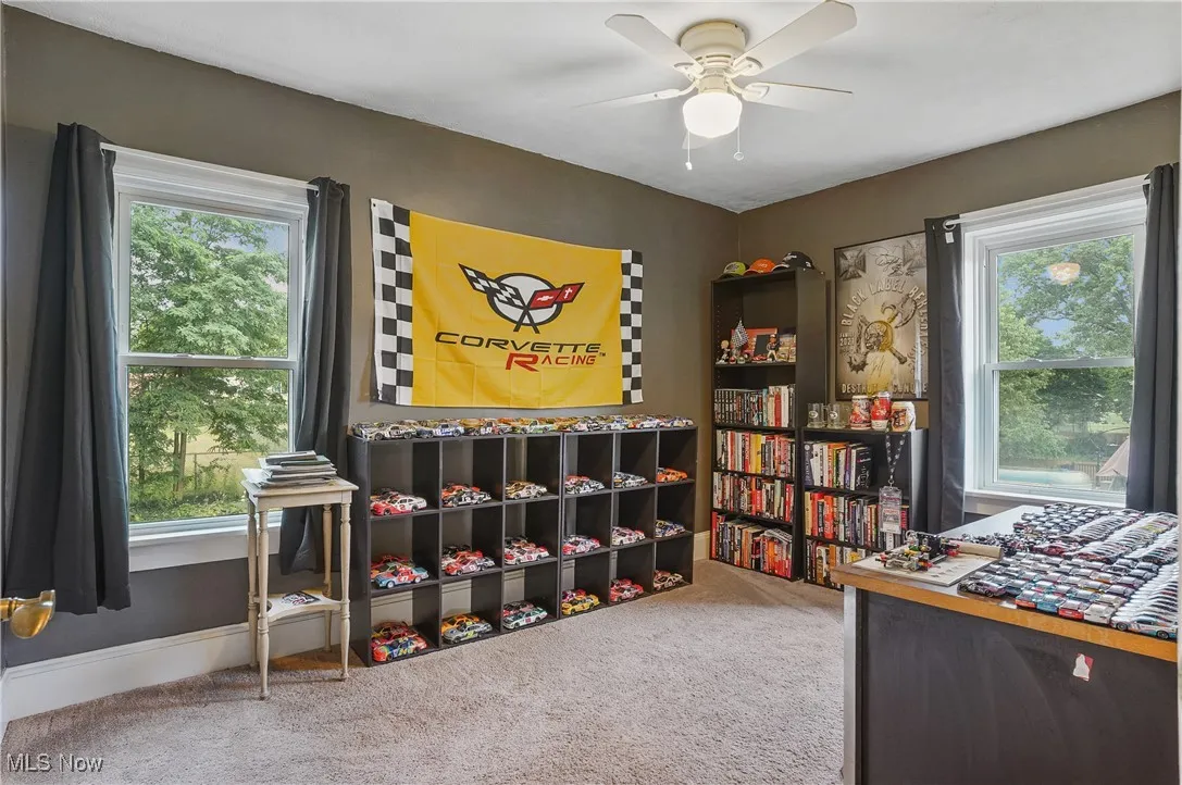 Carpeted home office featuring a ceiling fan and healthy amount of natural light
