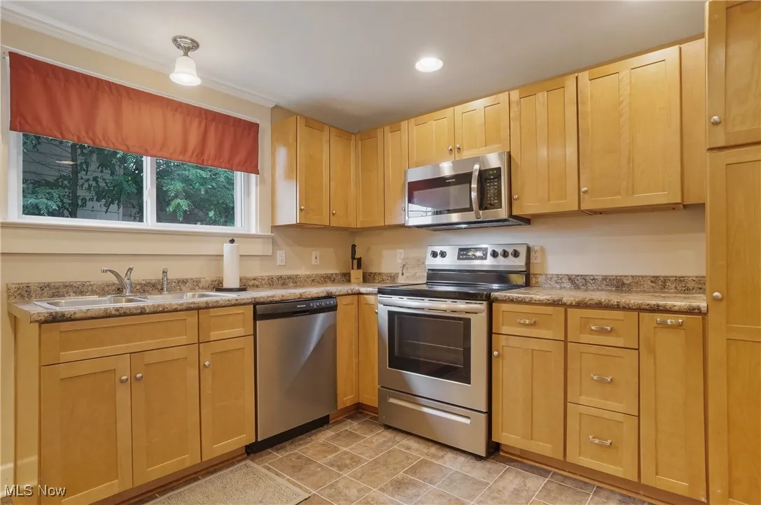 Kitchen featuring appliances with stainless steel finishes, light brown cabinetry, stone finish flooring, recessed lighting, and light countertops