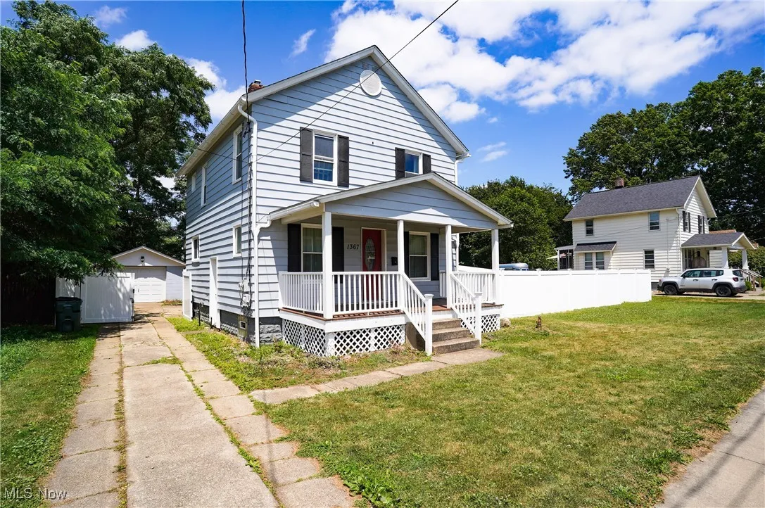 View of front of property with covered porch, a garage, driveway, and an outdoor structure