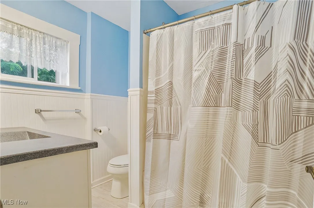 Full bathroom with wainscoting, vanity, and a shower with shower curtain