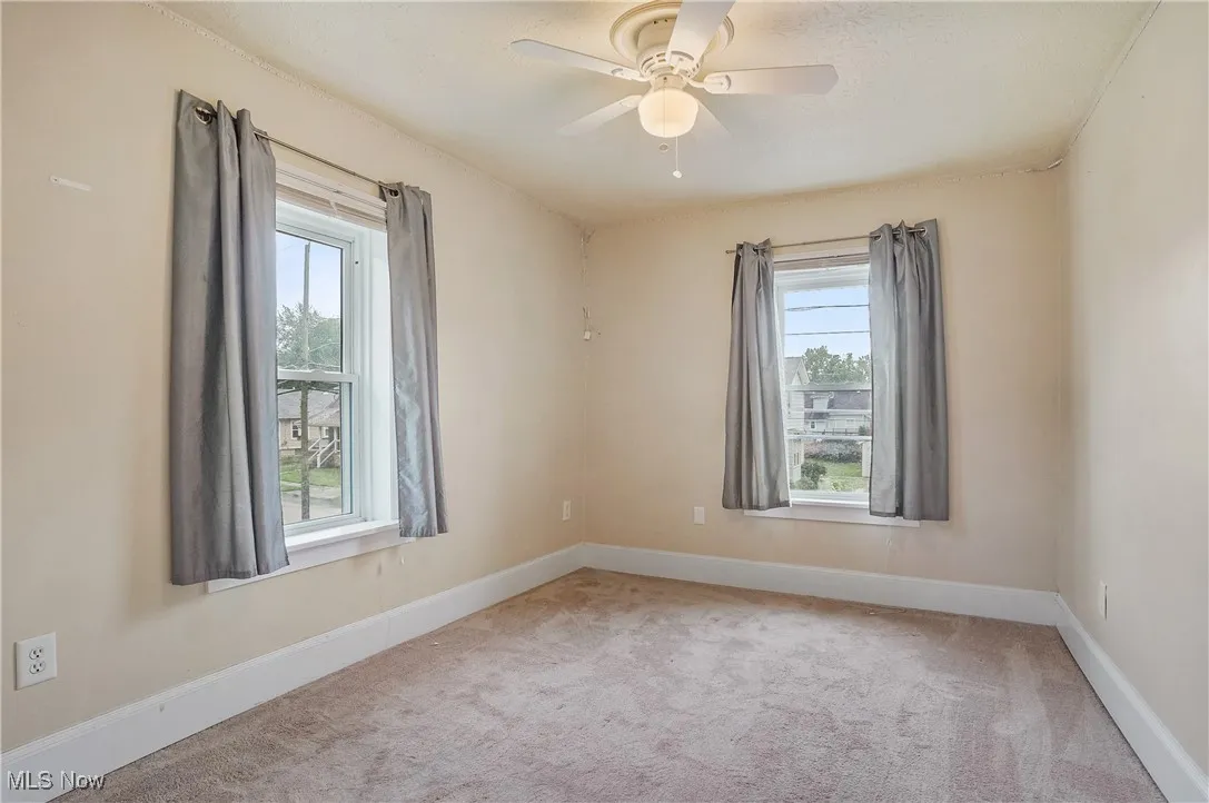 Unfurnished room featuring plenty of natural light, carpet flooring, and a ceiling fan