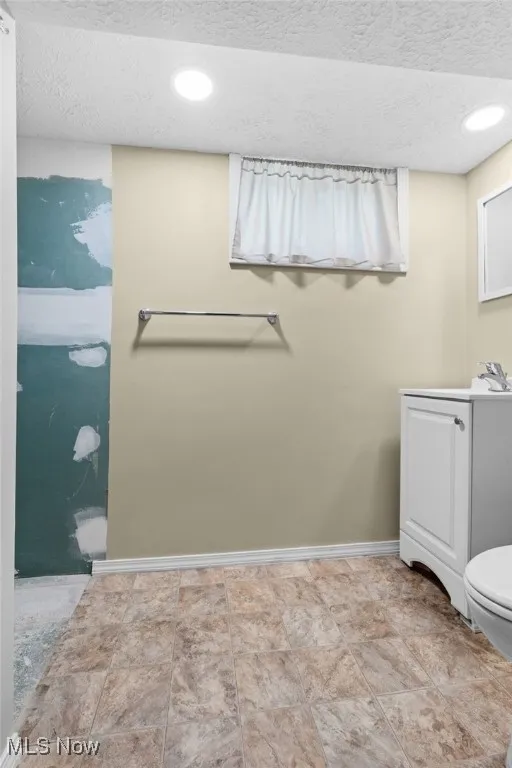 Full bathroom with vanity, a textured ceiling, and recessed lighting