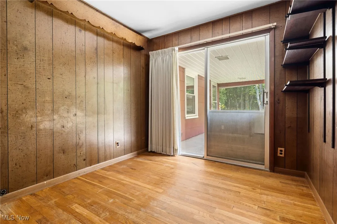 Empty room with hardwood / wood-style floors and wood walls